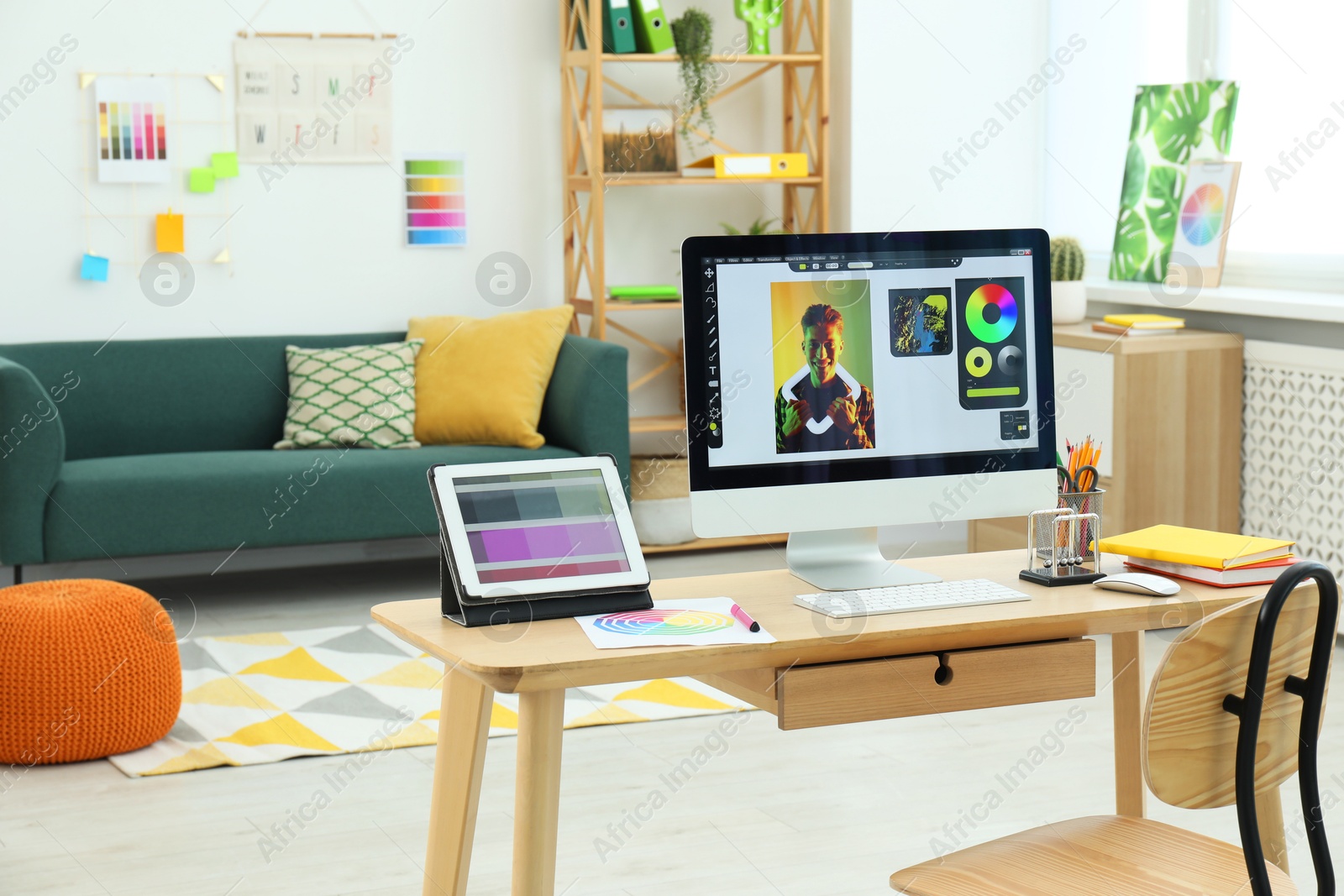 Photo of Designer's workplace with computer, tablet, color palette and stationery on wooden table indoors