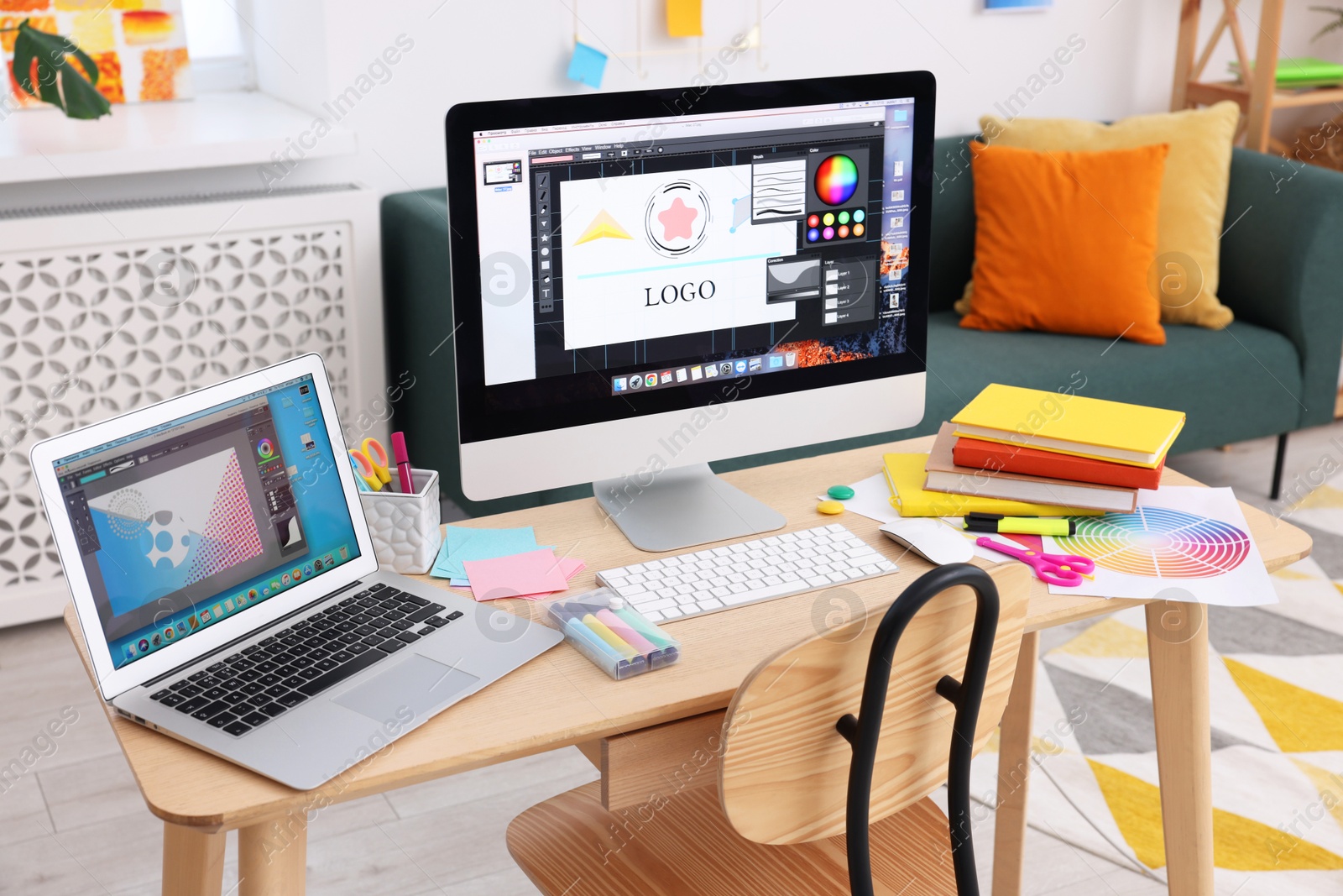 Photo of Designer's workplace with computer, laptop, color palette and stationery on wooden table indoors