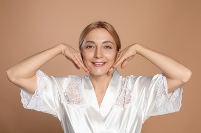 Portrait of smiling woman with healthy skin on beige background