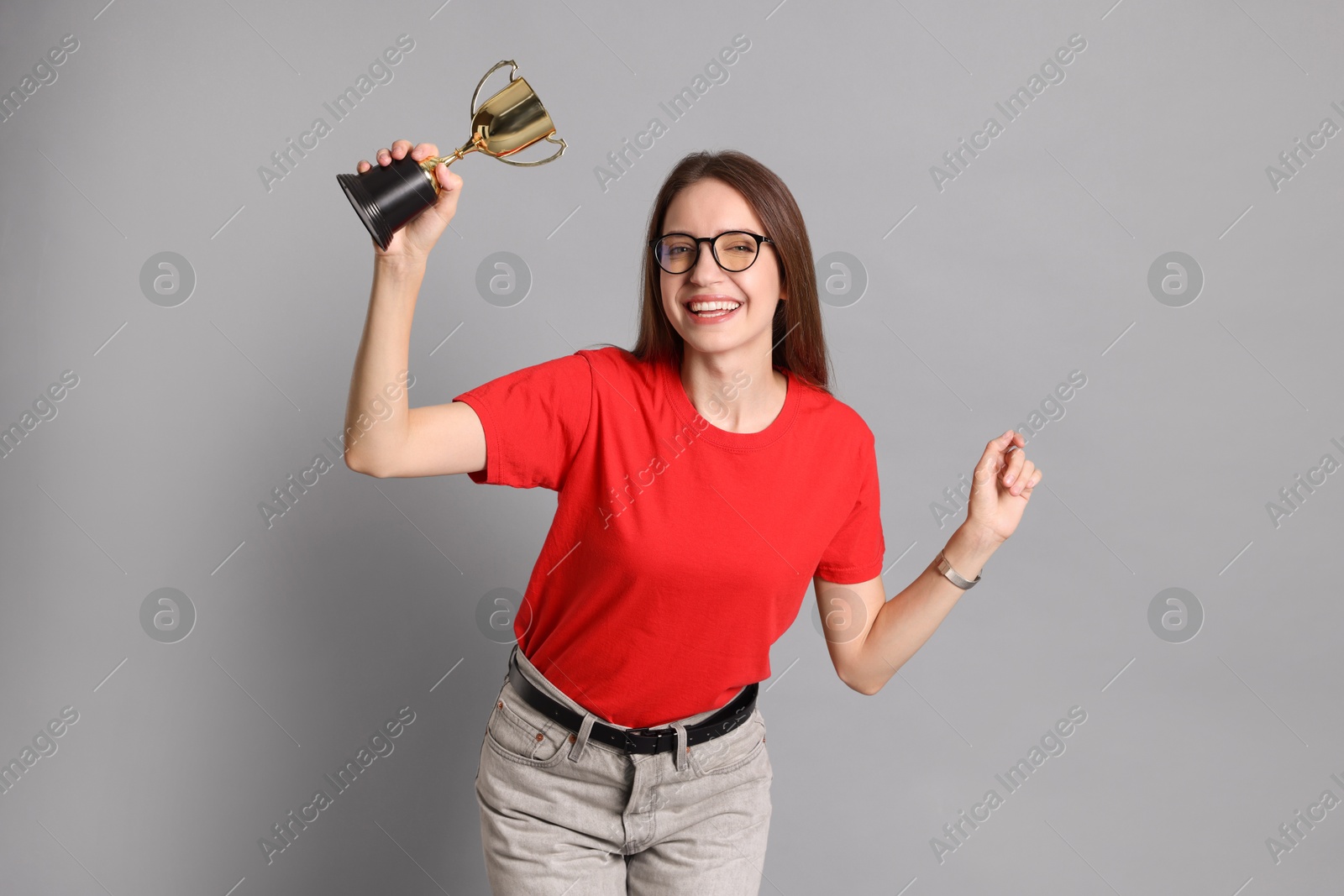 Photo of Happy winner with gold trophy cup on gray background