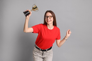 Happy winner with gold trophy cup on gray background