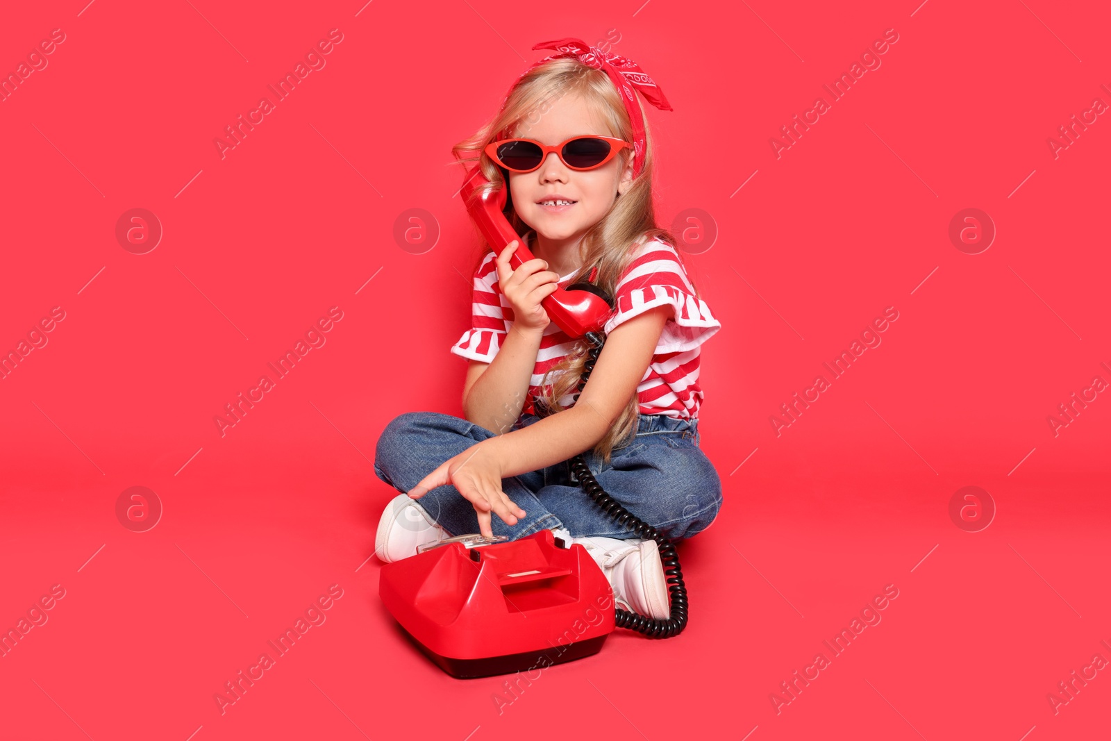 Photo of Cute little girl with telephone on red background