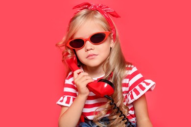 Photo of Cute little girl with handset of telephone on red background