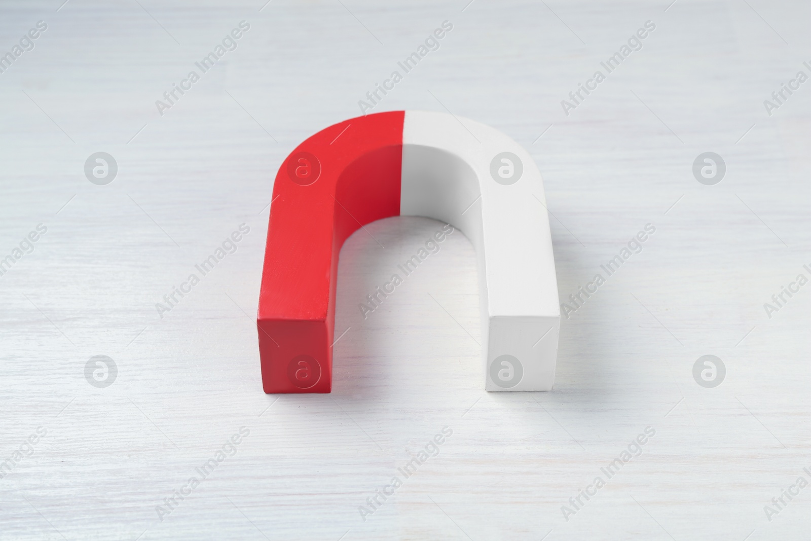 Photo of One horseshoe magnet on white wooden table