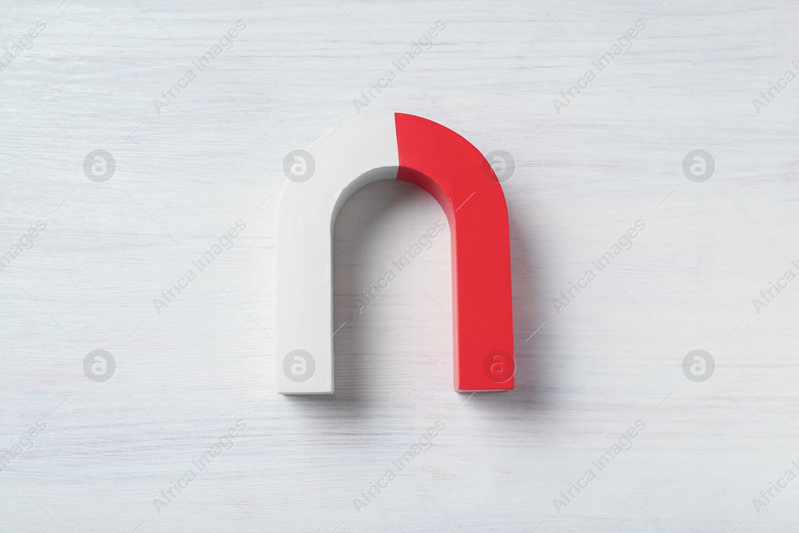 Photo of One horseshoe magnet on white wooden background, top view