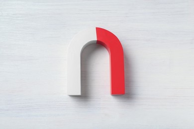 Photo of One horseshoe magnet on white wooden background, top view