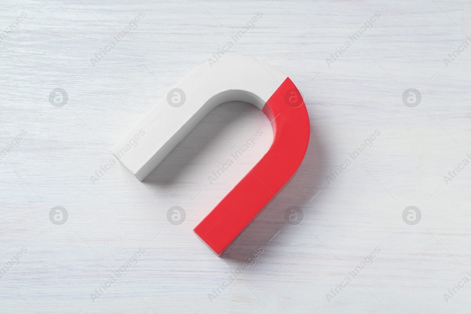 Photo of One horseshoe magnet on white wooden background, top view