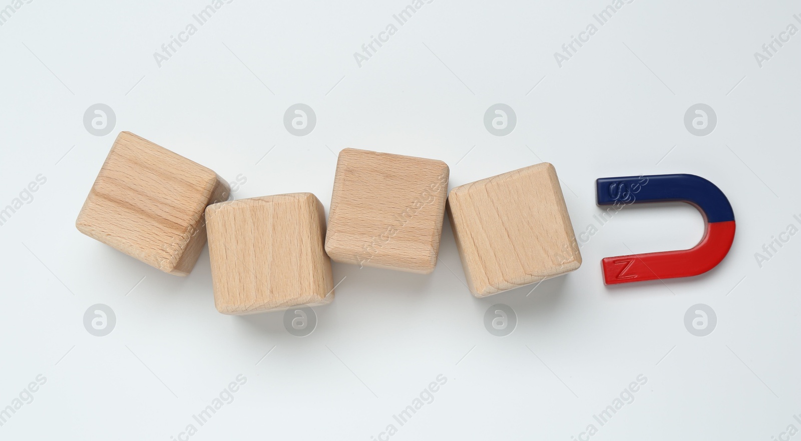 Photo of Magnet attracting wooden cubes on white background, flat lay