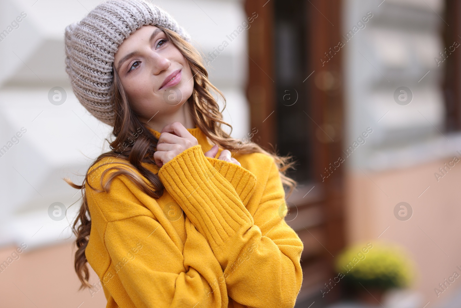 Photo of Beautiful young woman in warm sweater and hat outdoors, space for text. Autumn mood