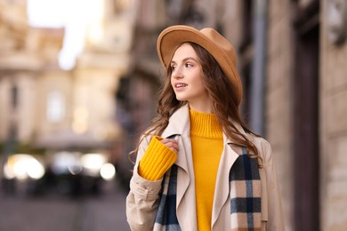 Photo of Charming young woman in stylish outfit on city street, space for text. Autumn season