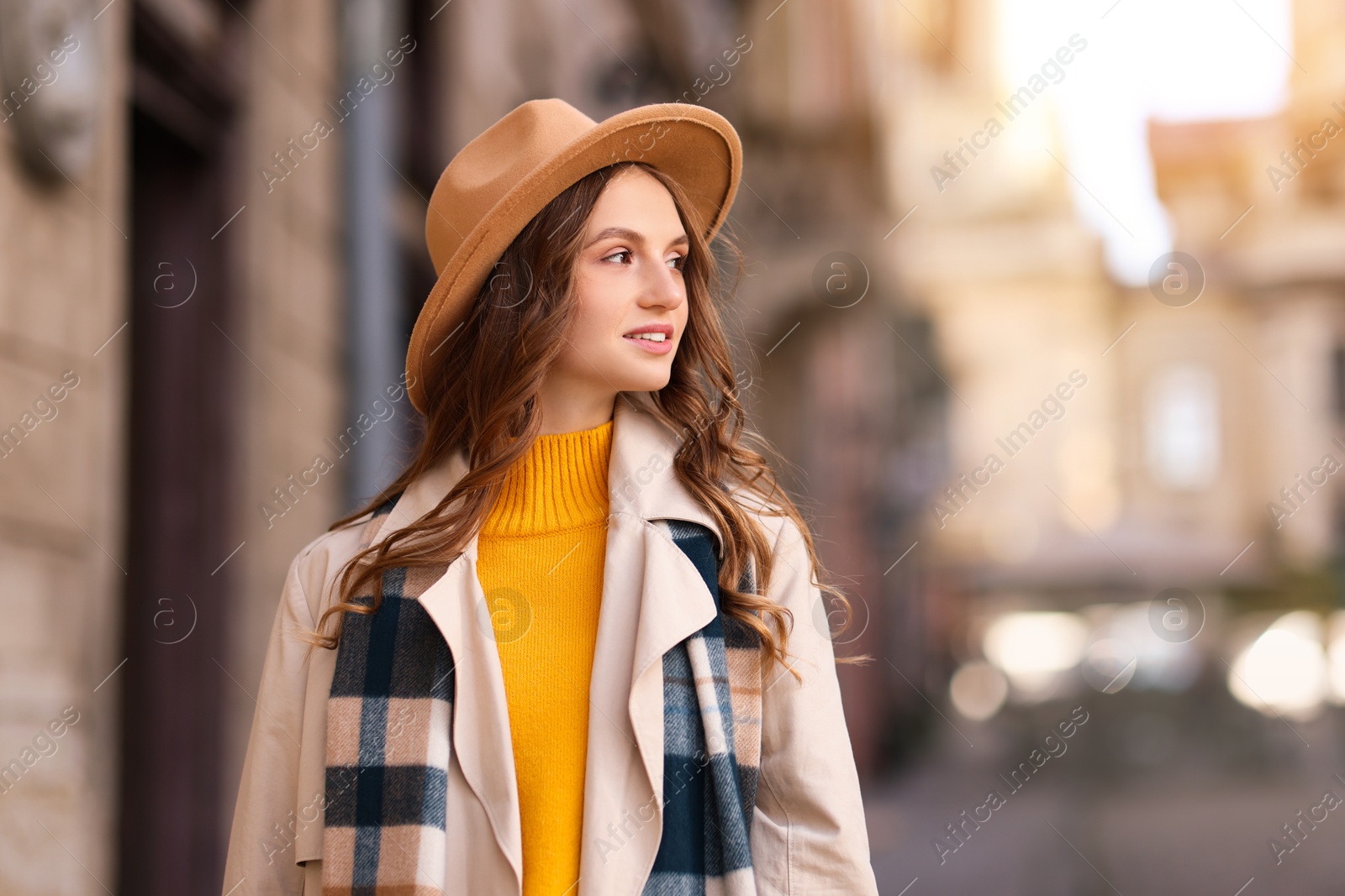 Photo of Charming young woman in stylish outfit on city street, space for text. Autumn season