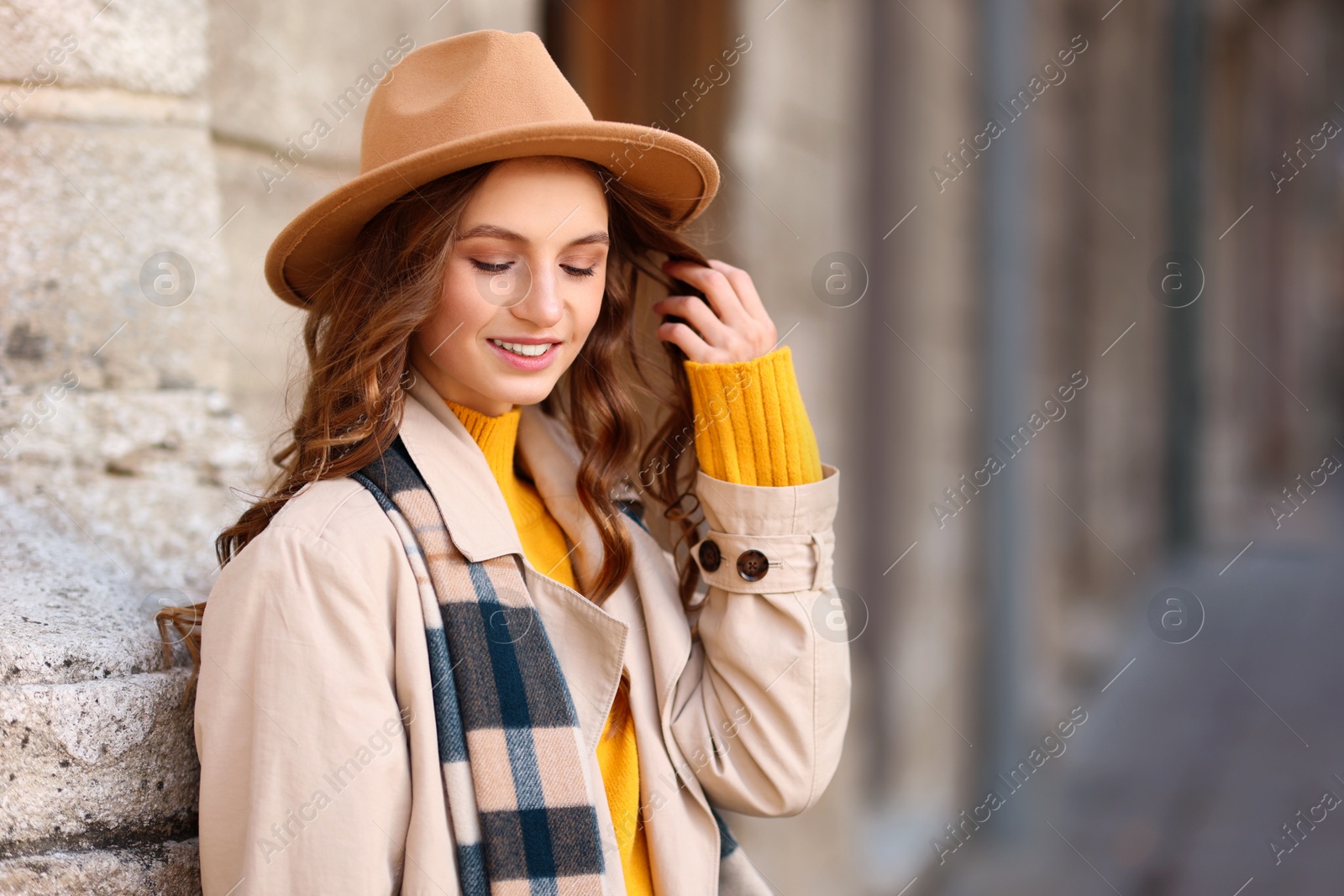 Photo of Charming young woman in stylish outfit on city street, space for text. Autumn season