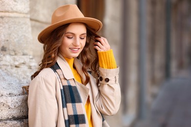 Photo of Charming young woman in stylish outfit on city street, space for text. Autumn season