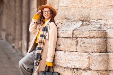 Photo of Charming young woman in stylish outfit on city street, space for text. Autumn season