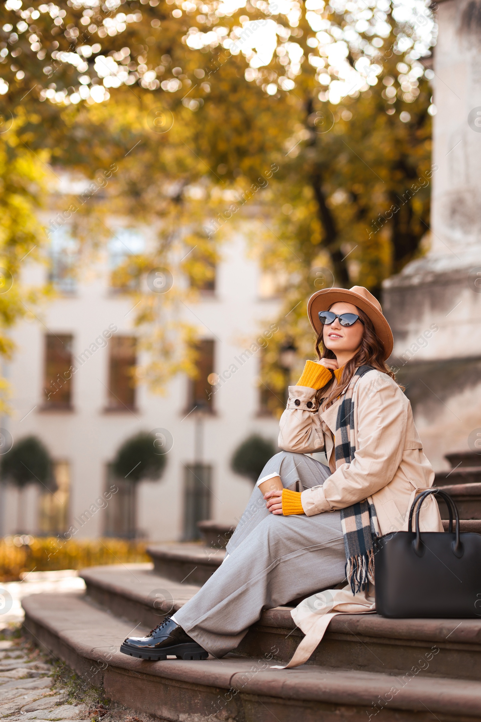 Photo of Charming young woman with cup of coffee on city street. Autumn season