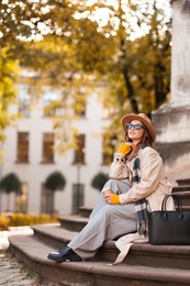 Photo of Charming young woman with cup of coffee on city street. Autumn season