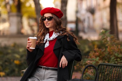 Photo of Stylish woman with cup of hot drink outdoors