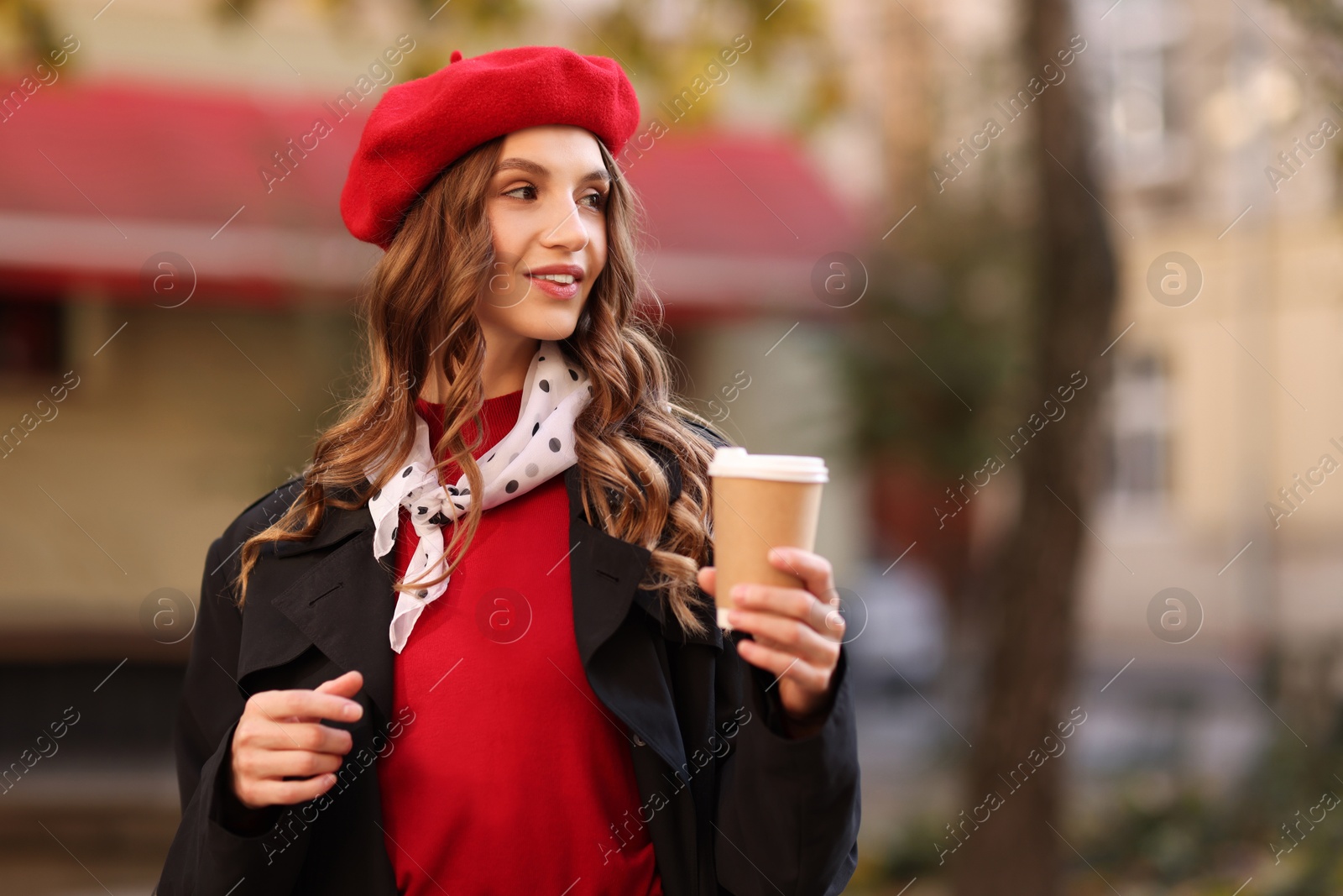 Photo of Stylish woman with cup of hot drink outdoors, space for text