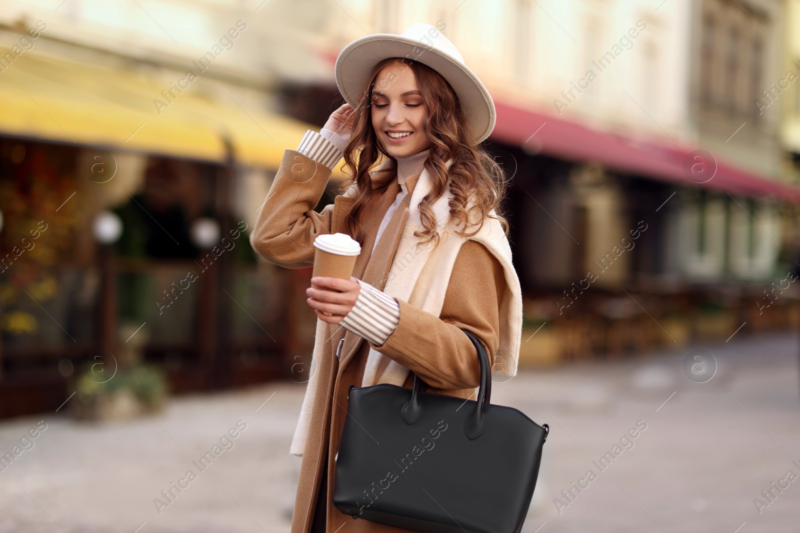 Photo of Beautiful young woman with hot drink on city street. Autumn style