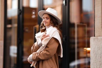 Charming young woman near shop on city street