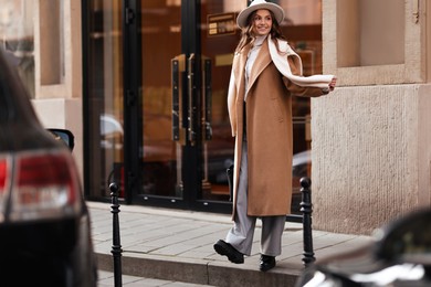 Photo of Young woman in beautiful outfit on city street. Autumn style