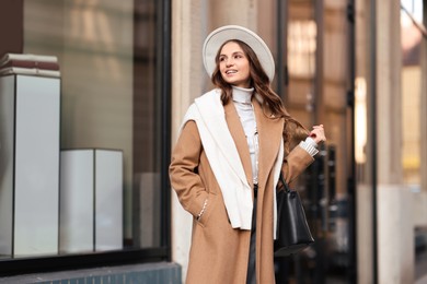 Photo of Young woman in beautiful outfit on city street. Autumn style