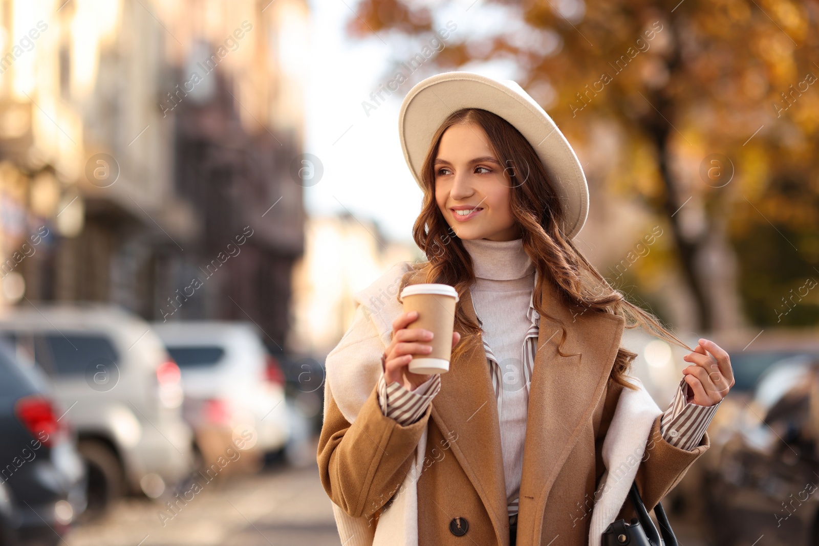 Photo of Stylish woman with cup of coffee outdoors, space for text. Autumn mood