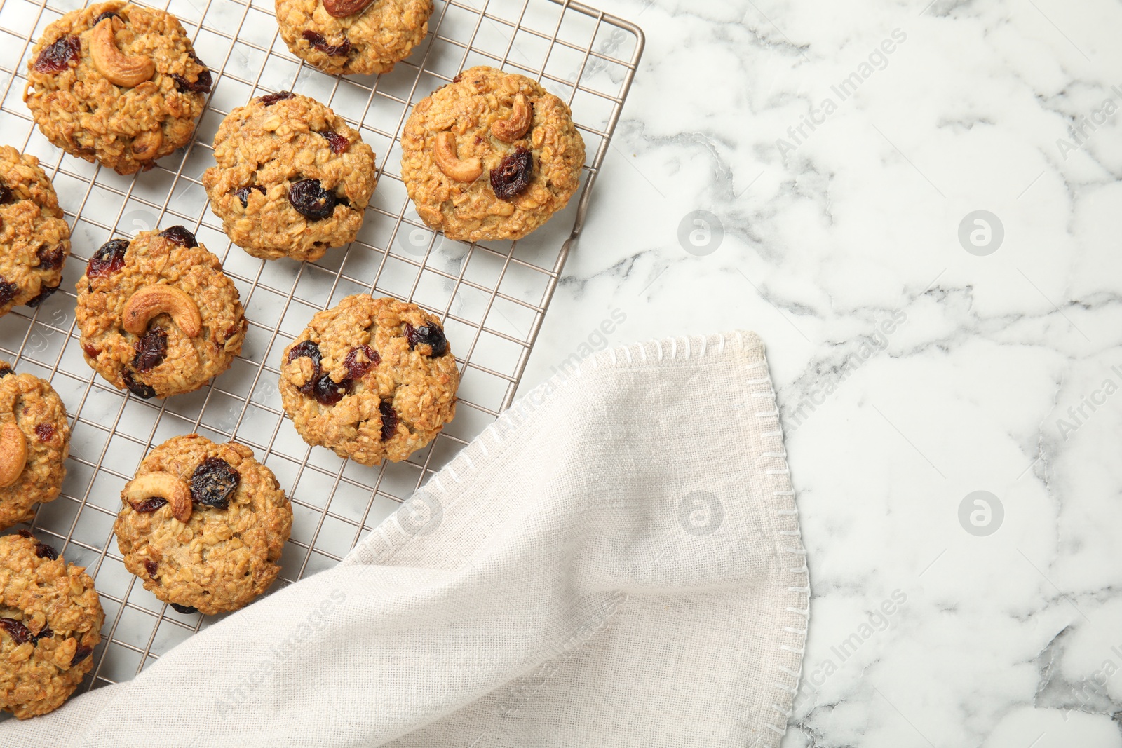 Photo of Delicious oatmeal cookies with raisins and nuts on white marble table, top view. Space for text