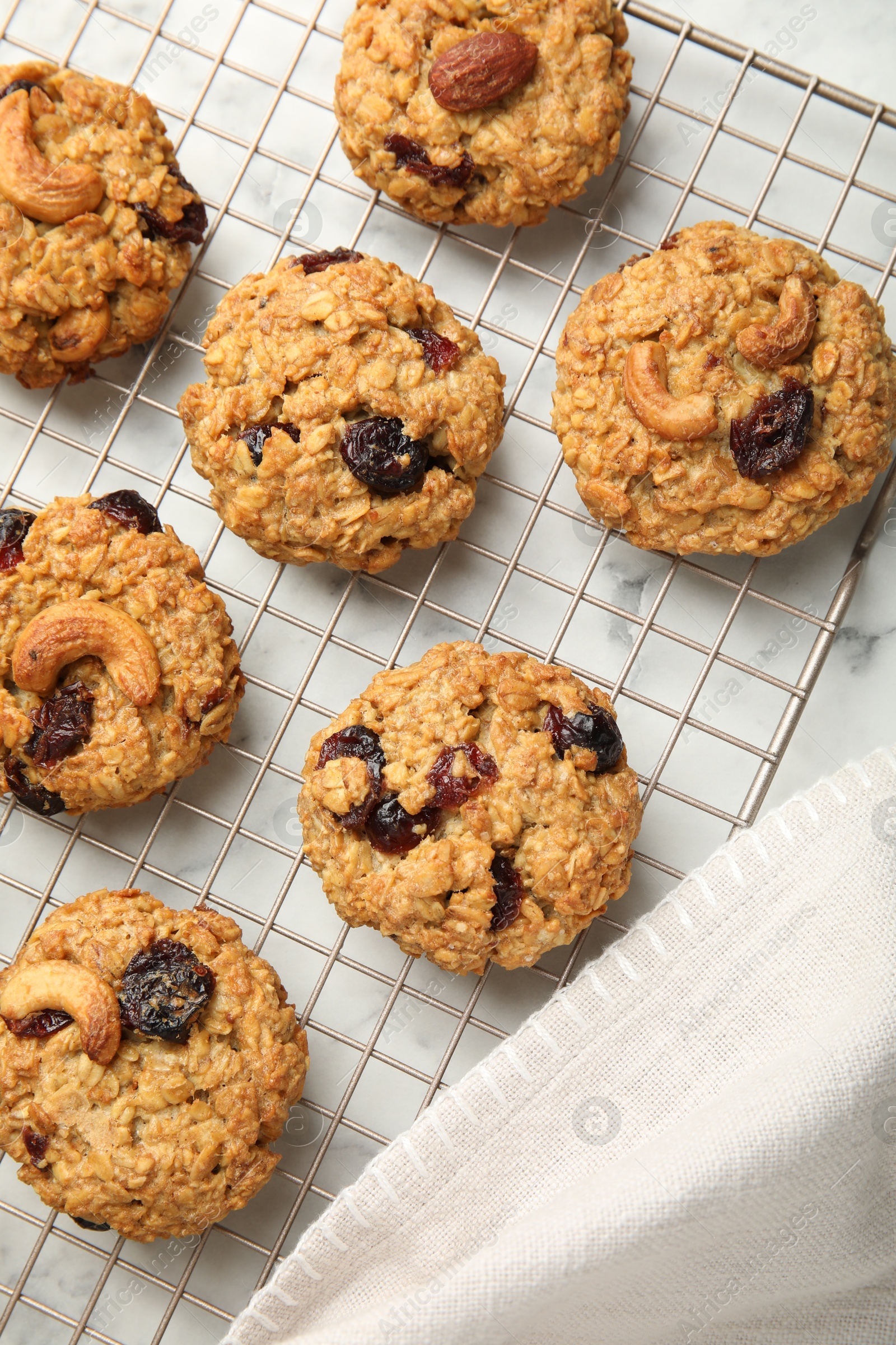 Photo of Delicious oatmeal cookies with raisins and nuts on white marble table, top view