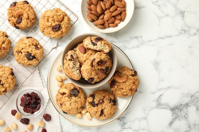 Photo of Delicious oatmeal cookies with raisins and nuts on white marble table, flat lay