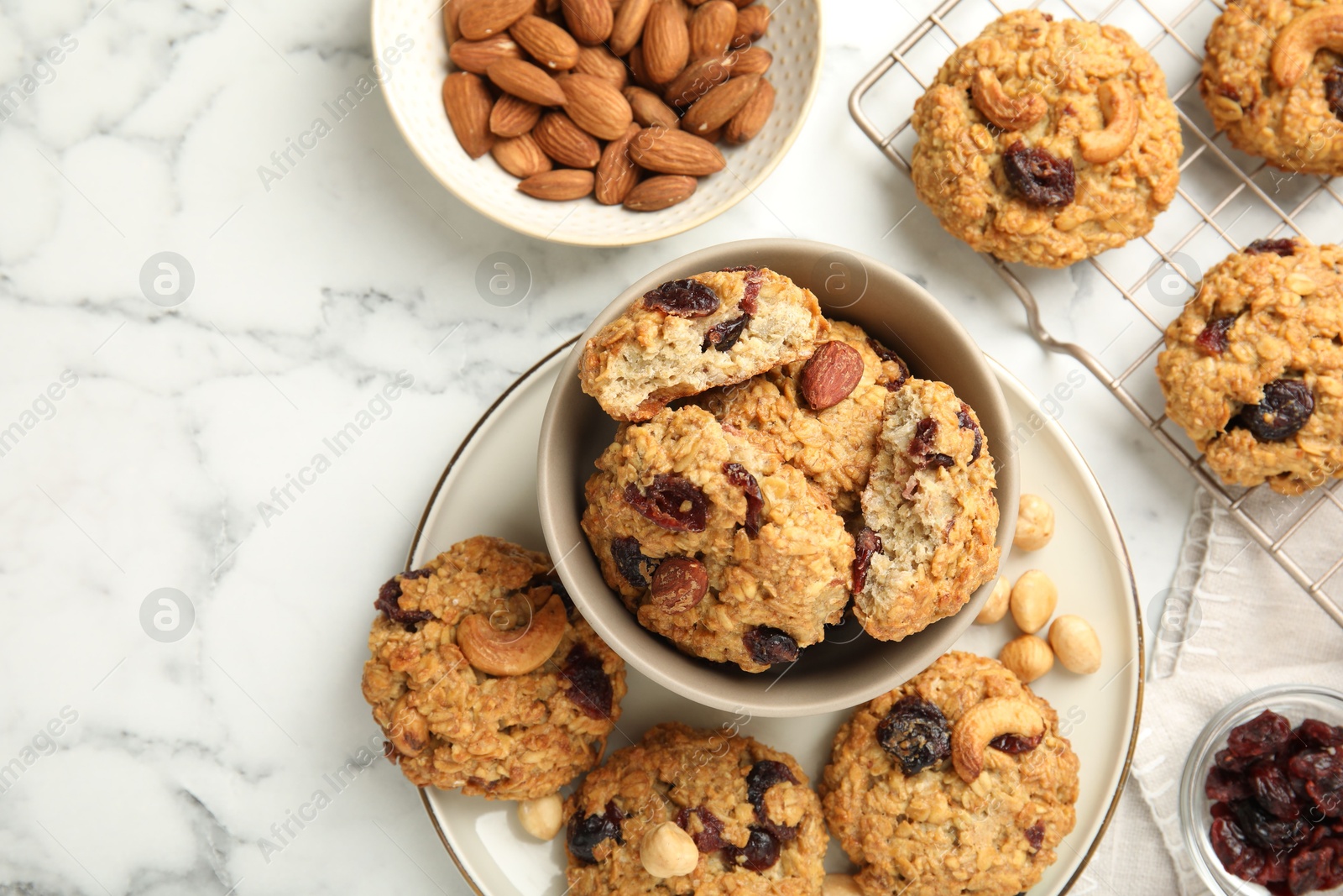 Photo of Delicious oatmeal cookies with raisins and nuts on white marble table, flat lay