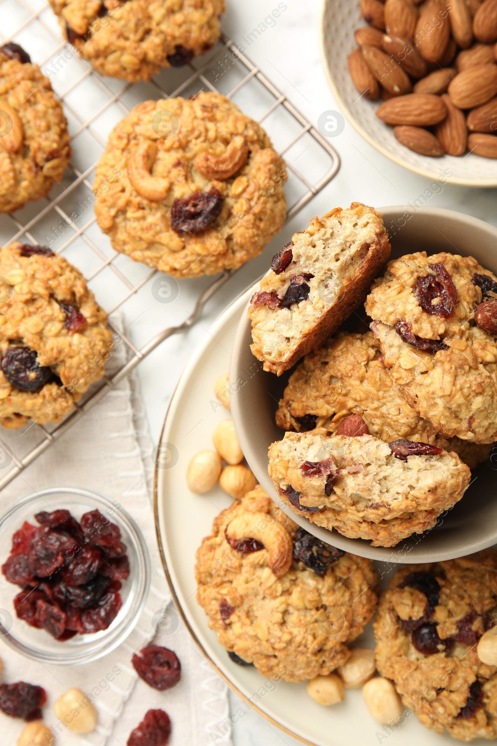 Photo of Delicious oatmeal cookies with raisins and nuts on white marble table, flat lay