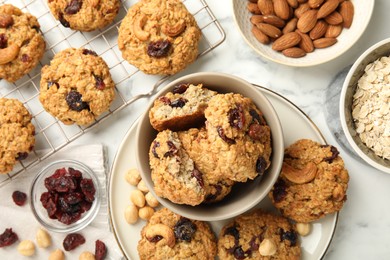 Photo of Delicious oatmeal cookies with raisins and nuts on white marble table, flat lay