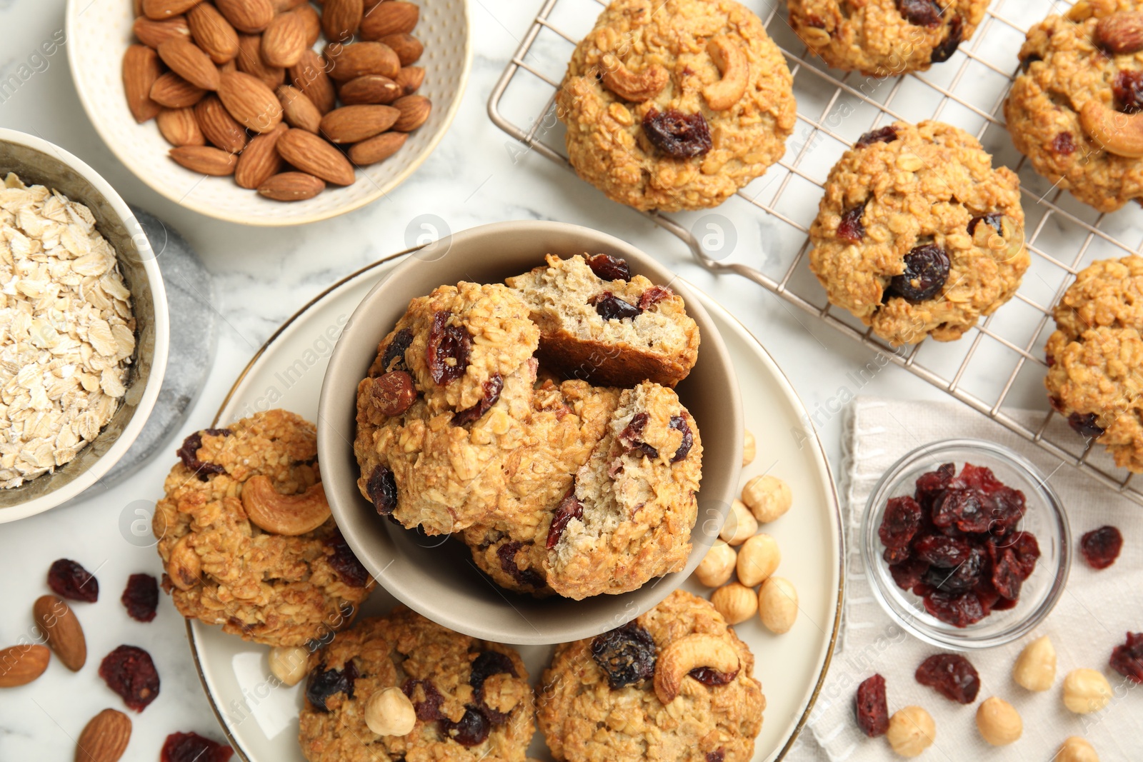 Photo of Delicious oatmeal cookies with raisins and nuts on white marble table, flat lay