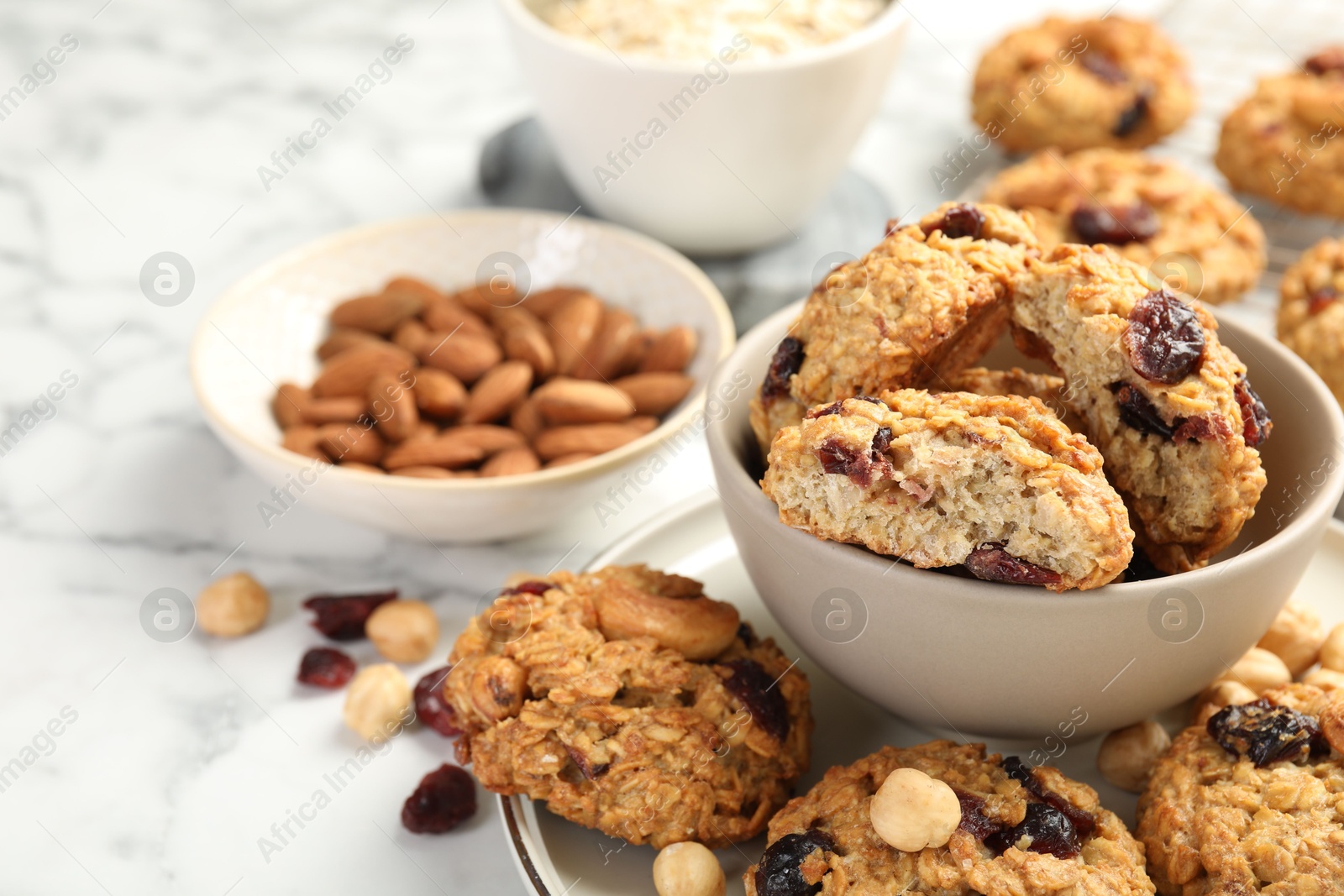 Photo of Delicious oatmeal cookies with raisins and nuts on white marble table, closeup