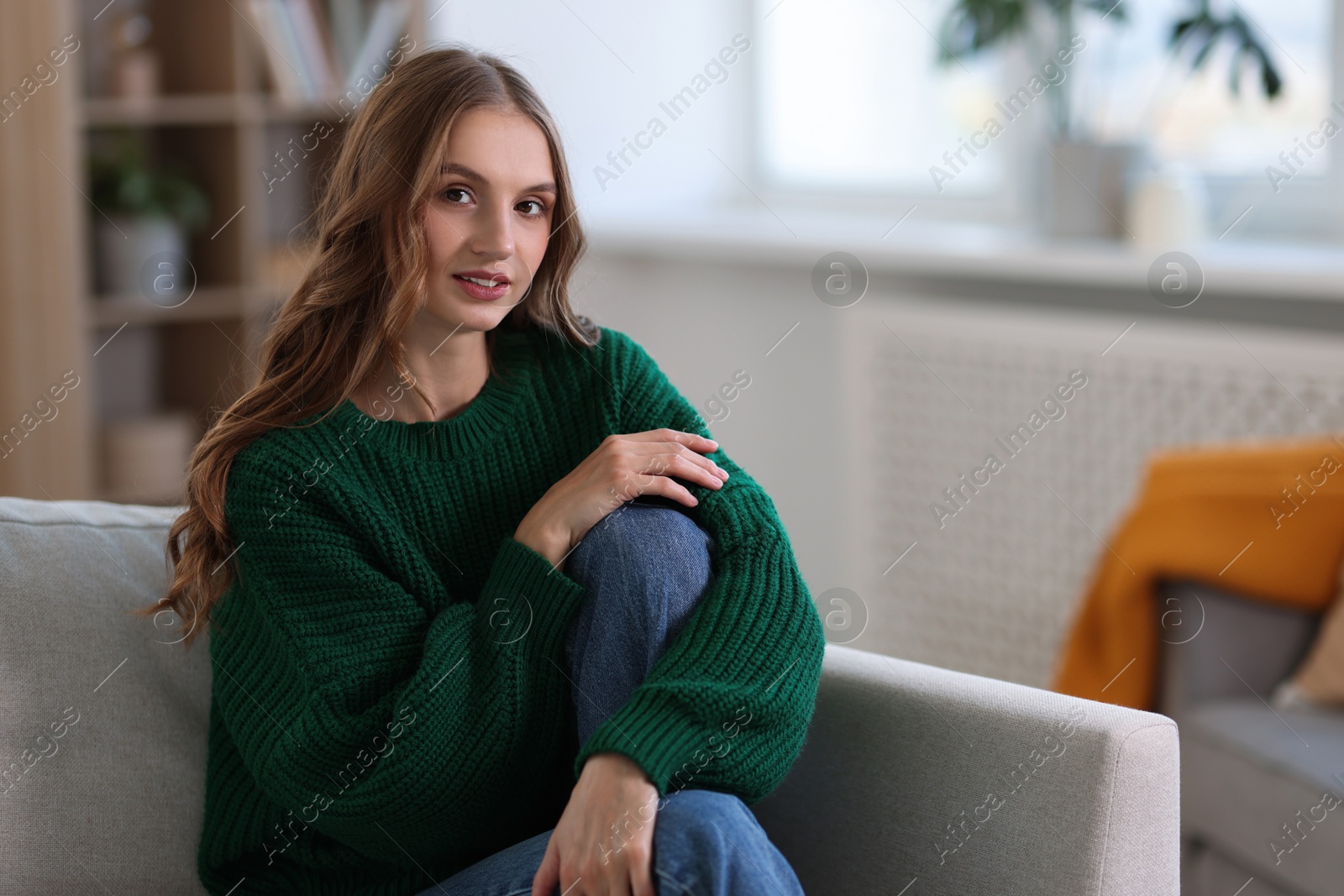 Photo of Charming young woman on sofa at home. Autumn atmosphere