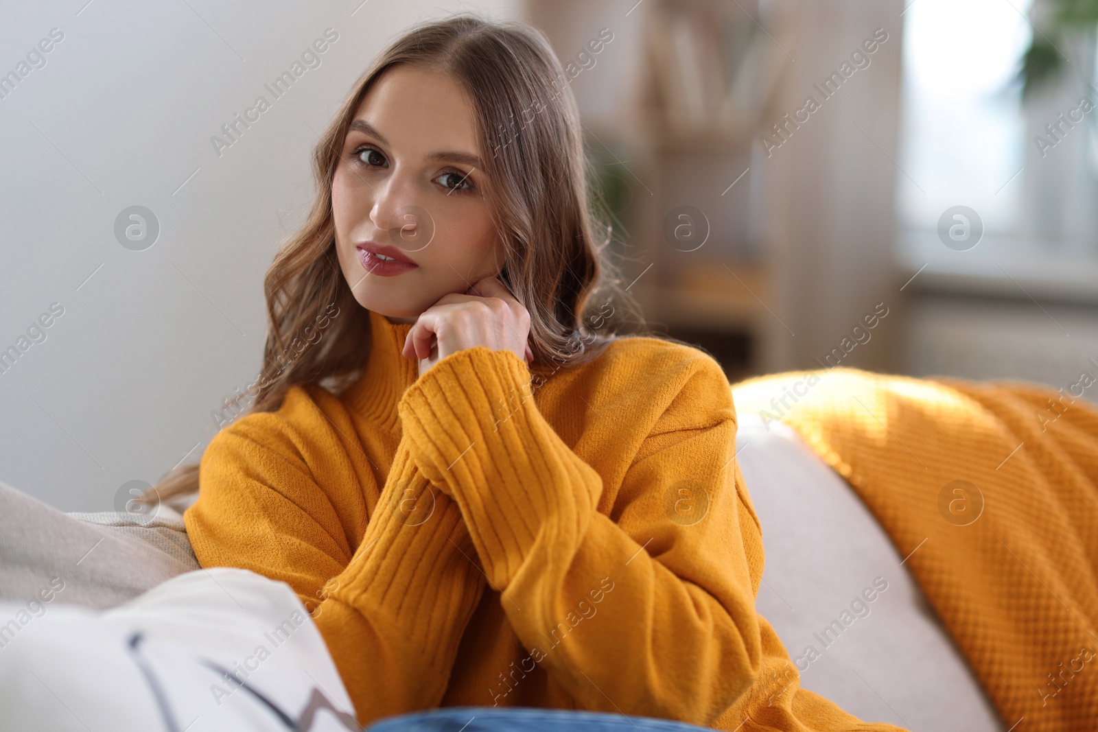 Photo of Charming young woman on sofa at home. Autumn atmosphere