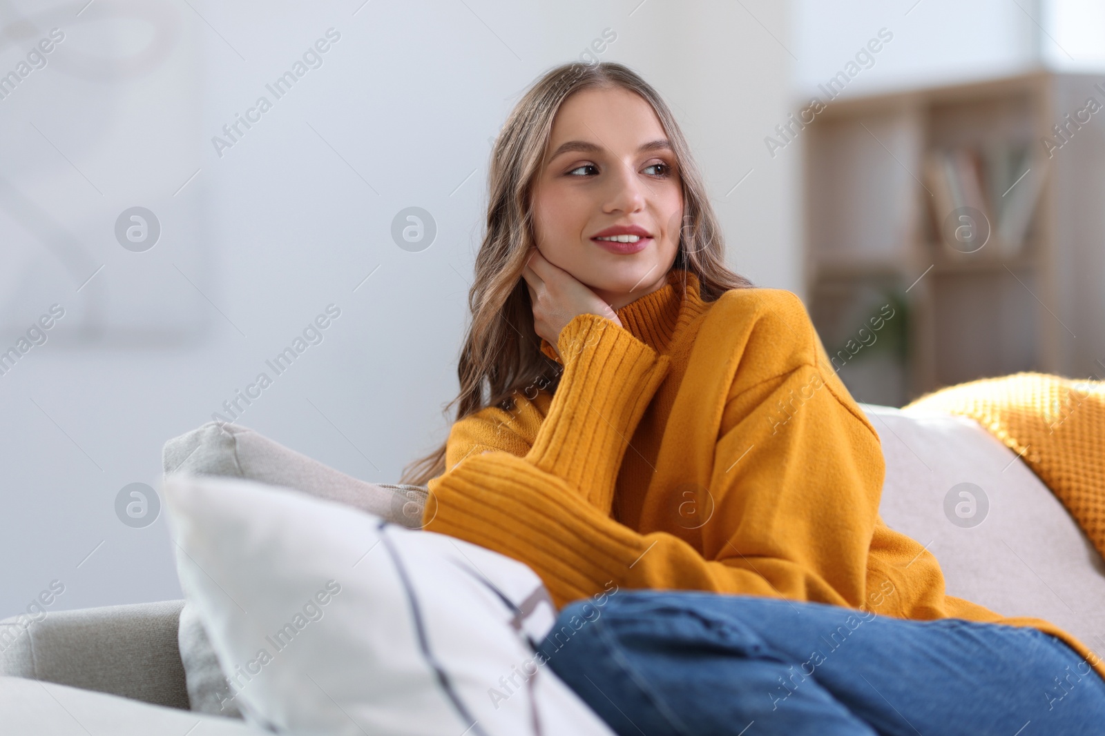 Photo of Charming young woman on sofa at home. Autumn atmosphere