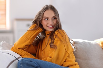 Charming young woman on sofa at home. Autumn atmosphere