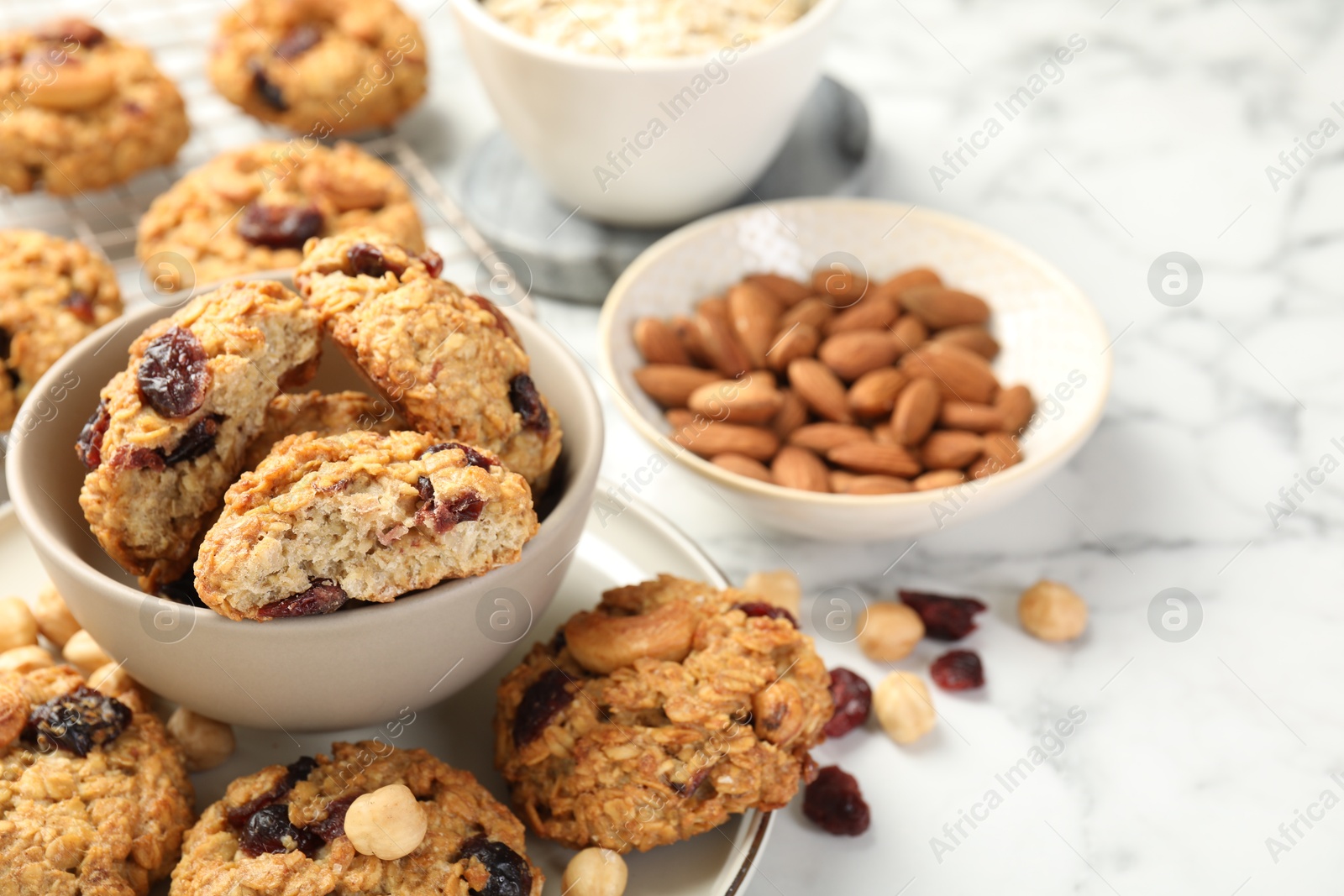 Photo of Delicious oatmeal cookies with raisins and nuts on white marble table, closeup