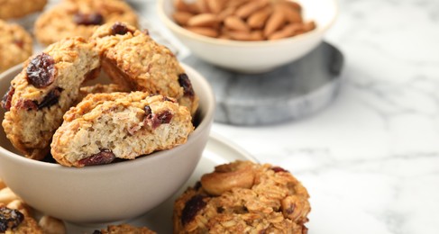 Delicious oatmeal cookies with raisins and nuts on white marble table, closeup. Space for text