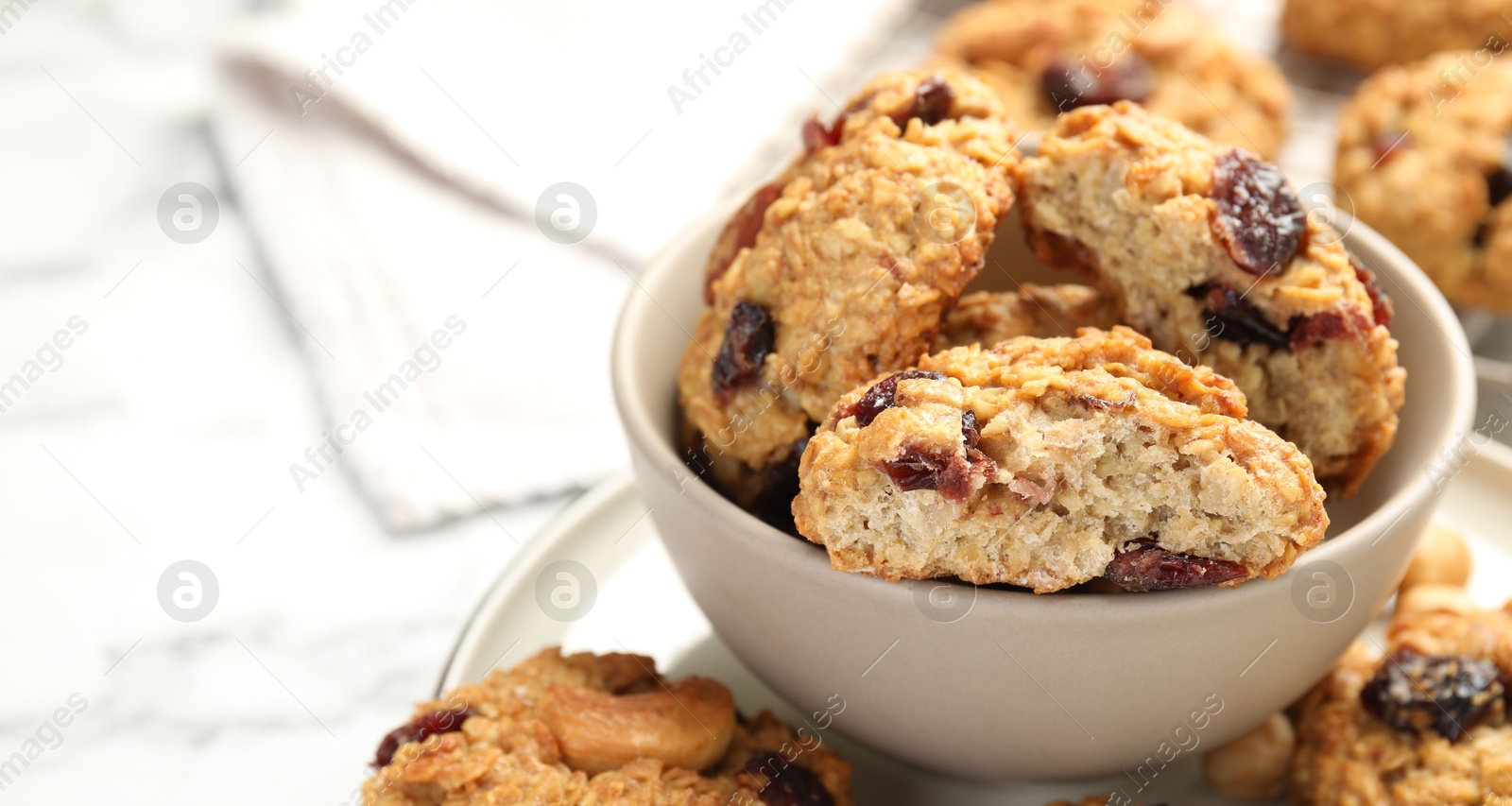 Photo of Delicious oatmeal cookies with raisins and nuts on white marble table, closeup. Space for text