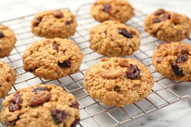 Photo of Delicious oatmeal cookies with raisins and nuts on white marble table, closeup