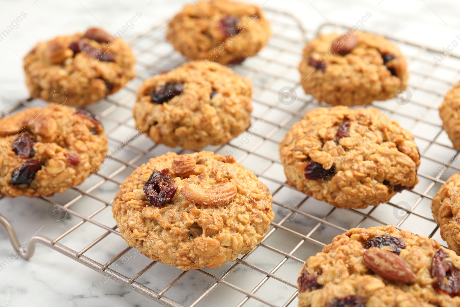 Photo of Delicious oatmeal cookies with raisins and nuts on white marble table, closeup