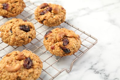 Photo of Delicious oatmeal cookies with raisins and nuts on white marble table, closeup