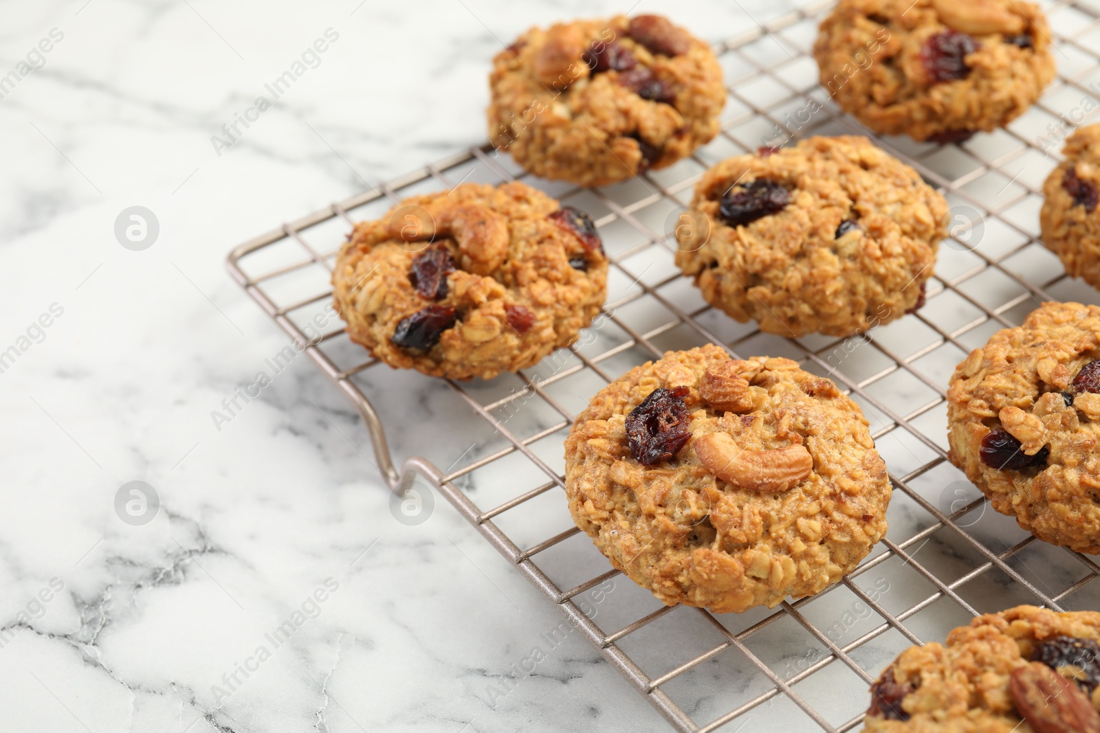 Photo of Delicious oatmeal cookies with raisins and nuts on white marble table, closeup