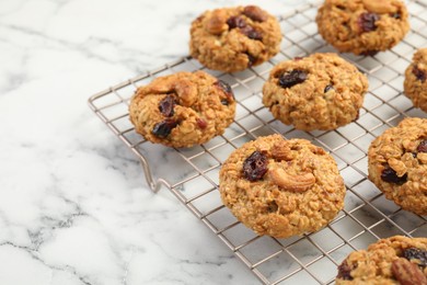 Delicious oatmeal cookies with raisins and nuts on white marble table, closeup