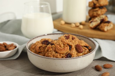 Delicious oatmeal cookies with raisins, nuts and milk on wooden table, closeup