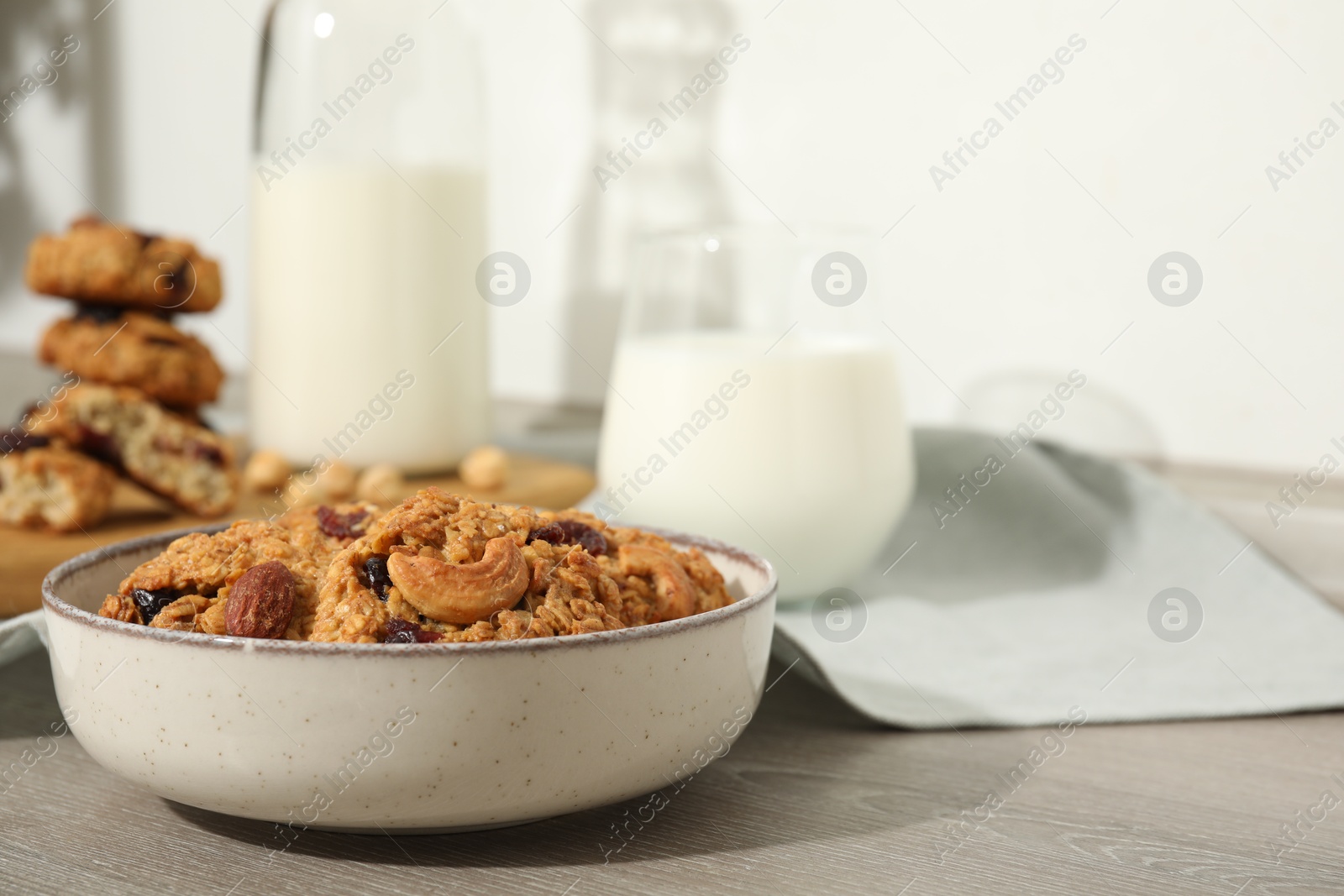 Photo of Delicious oatmeal cookies with raisins, nuts and milk on wooden table, closeup