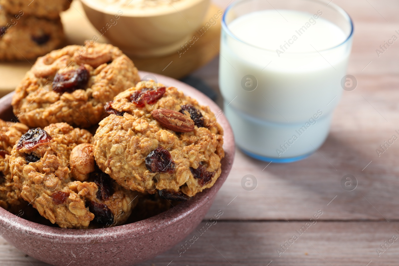 Photo of Delicious oatmeal cookies with raisins, nuts and milk on wooden table, closeup